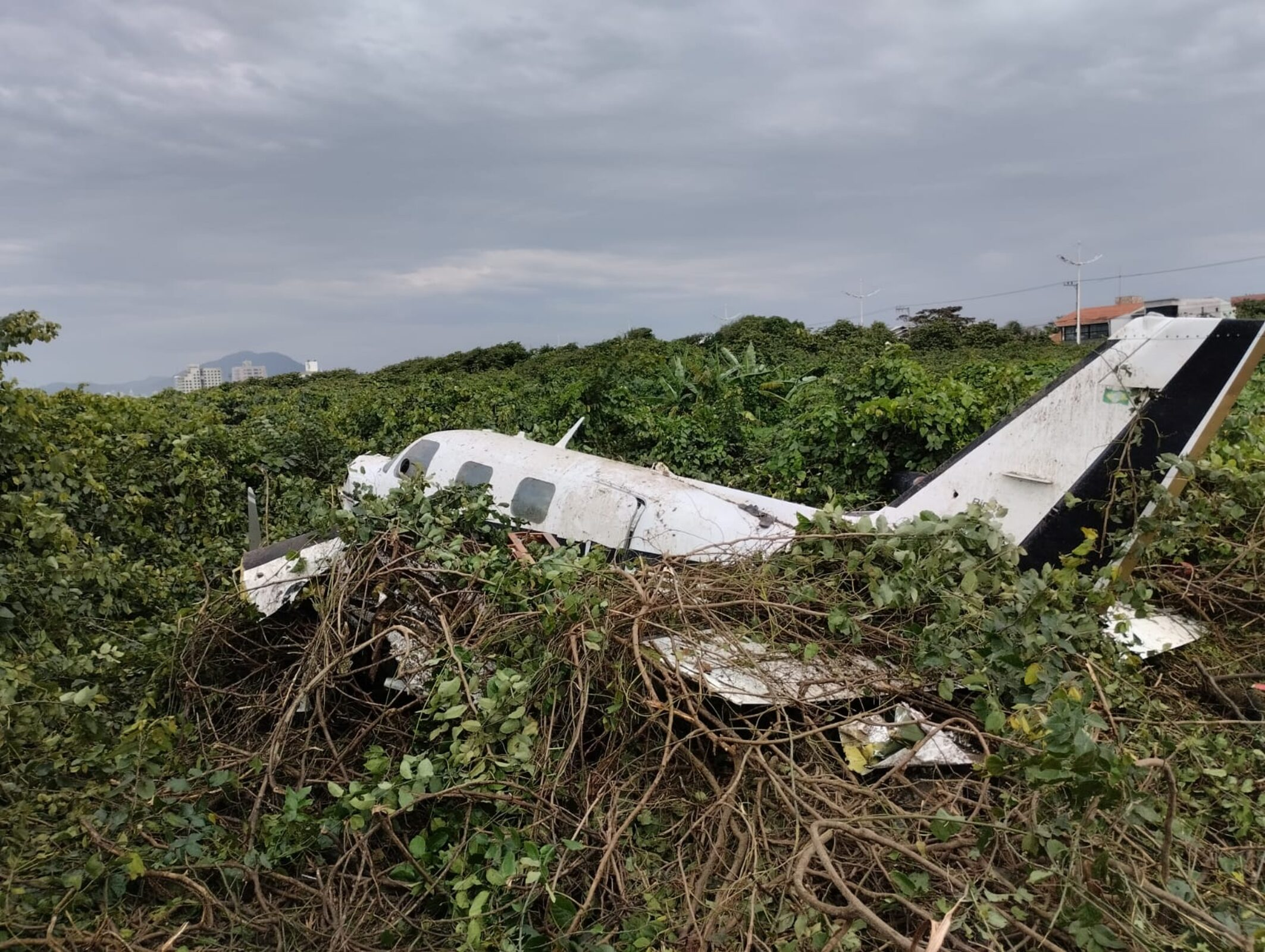 Imagens fornecidas pelos Bombeiros mostram o avi&atilde;o parcialmente destru&iacute;do em uma &aacute;rea de restinga da praia e tomado pela vegeta&ccedil;&atilde;o