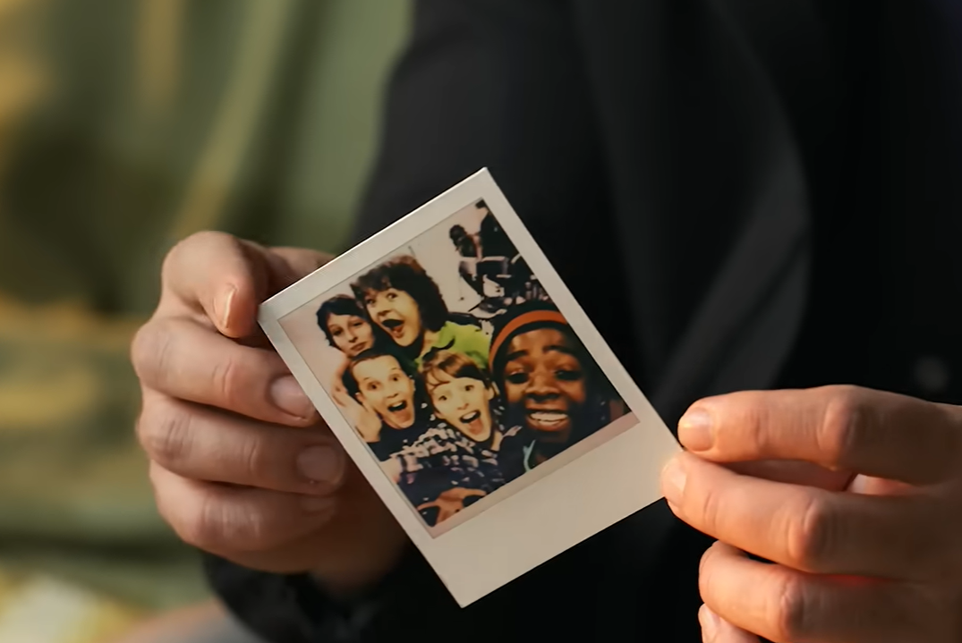 Os atores aparecem folheando fotografias em estilo polaroid que registram diferentes fases das grava&ccedil;&otilde;es de "Stranger Things"