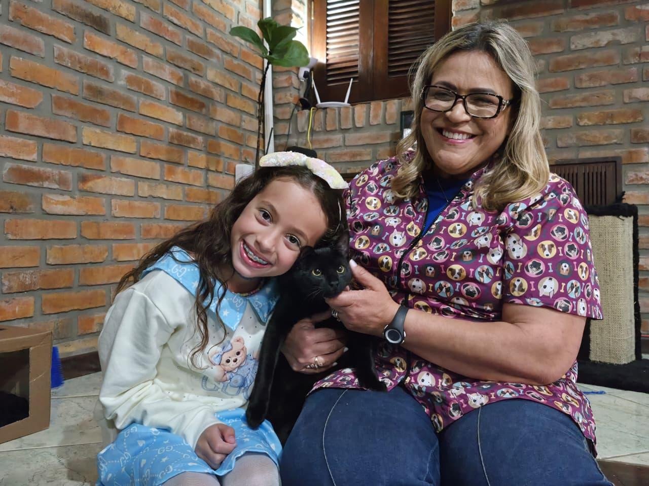 Gato foi entregue pela empres&aacute;ria Adriane Soares (dir.), da Guardi&otilde;es Pet (onde ele foi abandonado), para a pequena Liz (esq.), neta dos novos tutores