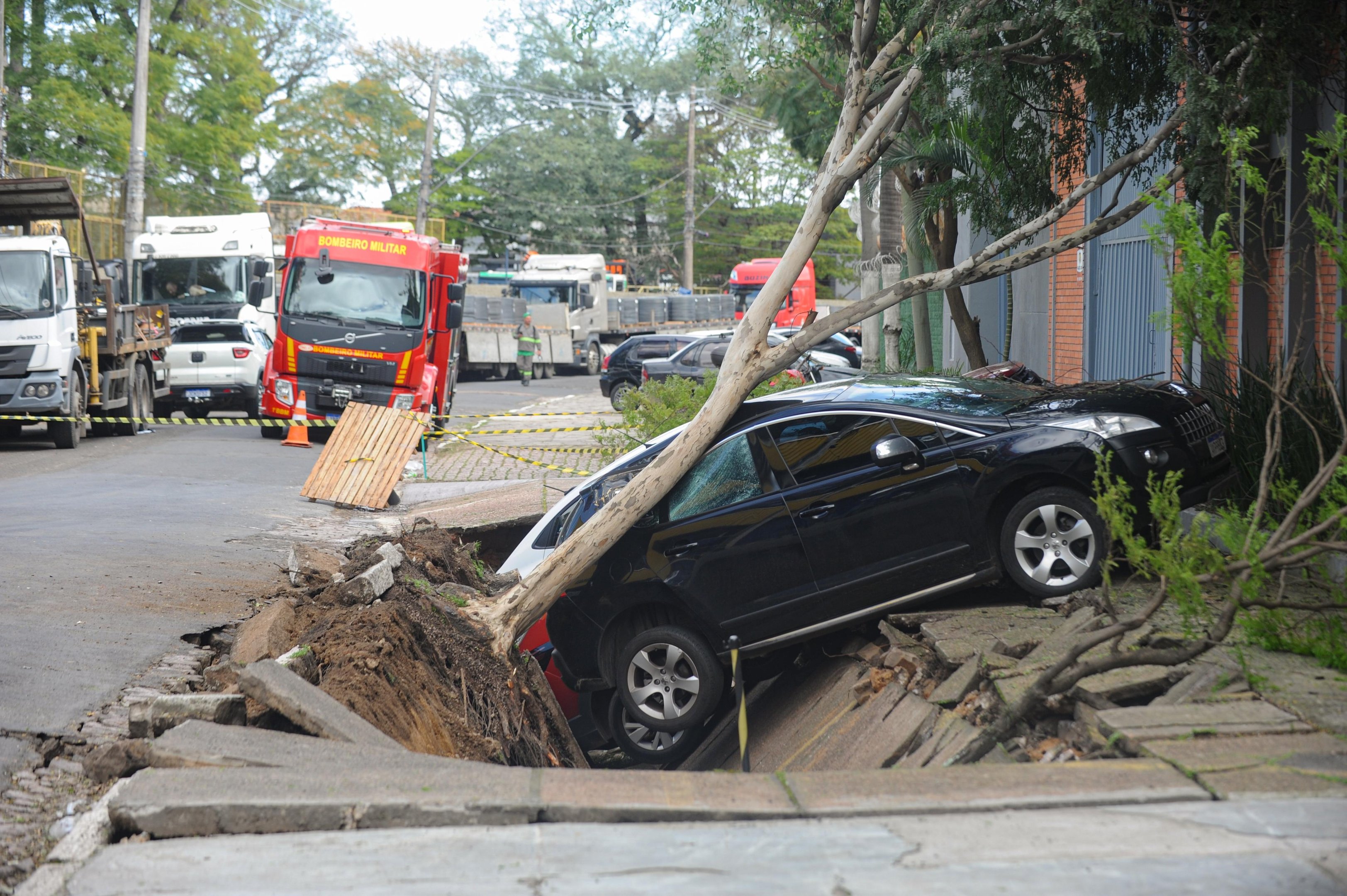 Tr&ecirc;s carros ca&iacute;ram em buraco que se abriu num estacionamento