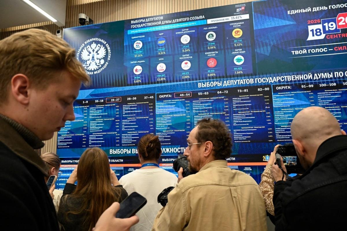 Membros da imprensa se re&uacute;nem em frente a uma enorme tela que exibe os resultados das elei&ccedil;&otilde;es parlamentares da R&uacute;ssia