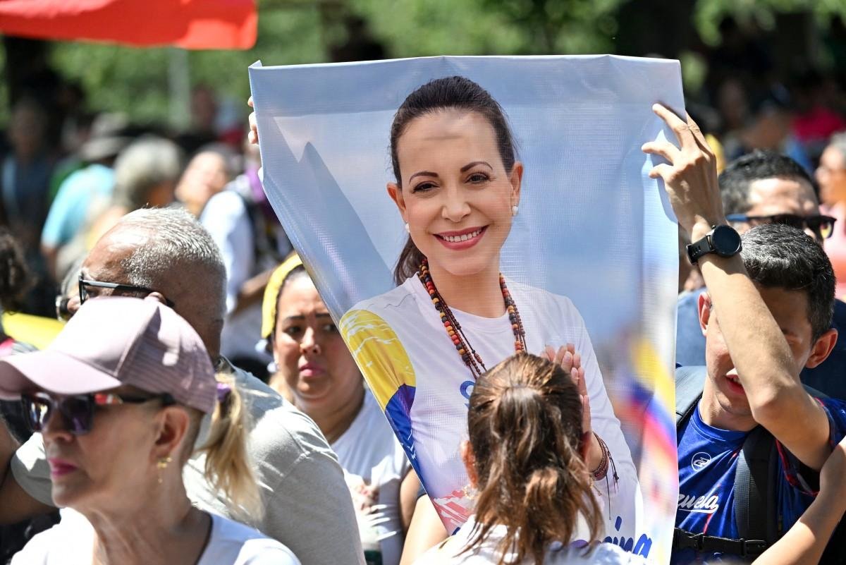 Uma manifestante mostra um cartaz com a imagem da l&iacute;der opositora Maria Corina Machado durante uma marcha para exigir o retorno dela &agrave; Venezuela