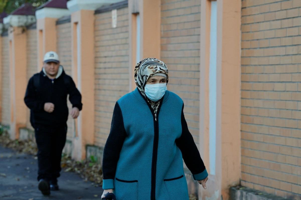 Uma mulher usando m&aacute;scara passa em frente ao instituto anti-peste na cidade de Irkutsk