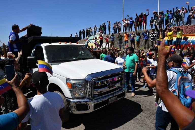 Pessoas comemoram enquanto caminh&otilde;es com ajuda humanit&aacute;ria para a Venezuela se aproximam da fronteira Brasil-Venezuela em Pacaraima, em Roraima