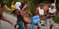 Homem ferido é levado por às pressas após um conflito na Venezuela