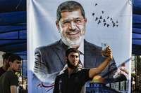 Jovem faz selfie junto a poster de Mohammed Morsi no sul da Faixa de Gaza.