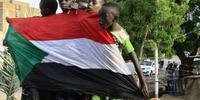 Garotos carregam bandeira nacional um dia depois que líderes assinaram acordo que determina transição civil no Sudão