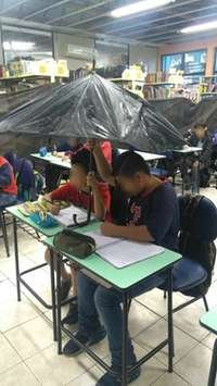 Alunos utilizaram um guarda-chuva para se proteger das coteiras da sala de aula