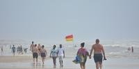 Veranistas aproveitaram sábado nublado para caminhar na beira da praia em Imbé