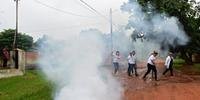 Funcionário atravessam rua durante ação de fumegação em San Lorenzo, Paraguai