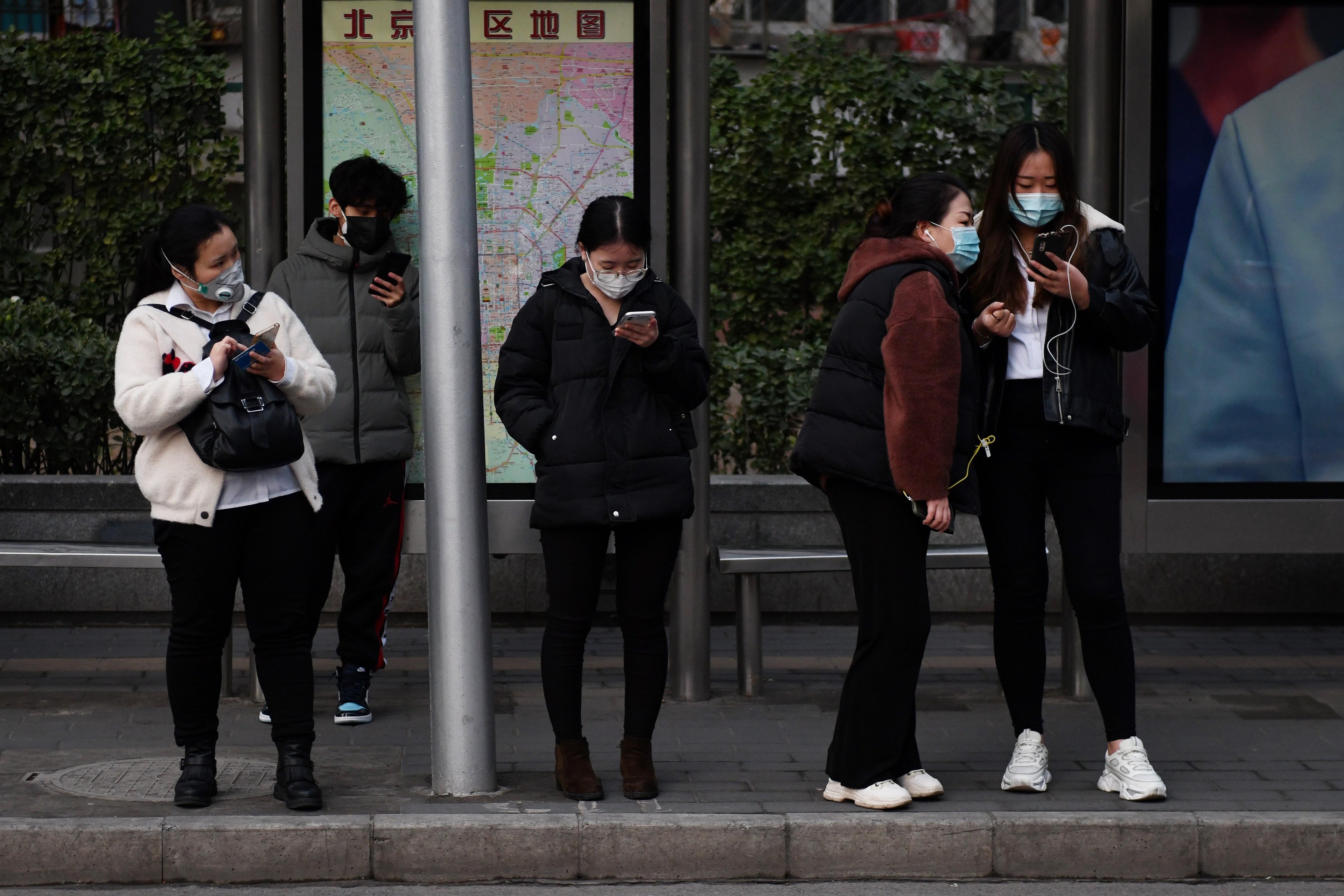 Chineses usam m&aacute;scaras como medida preventiva contra o coronav&iacute;rus enquanto esperam um &ocirc;nibus em Pequim