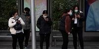 Chineses usam máscaras como medida preventiva contra o coronavírus enquanto esperam um ônibus em Pequim
