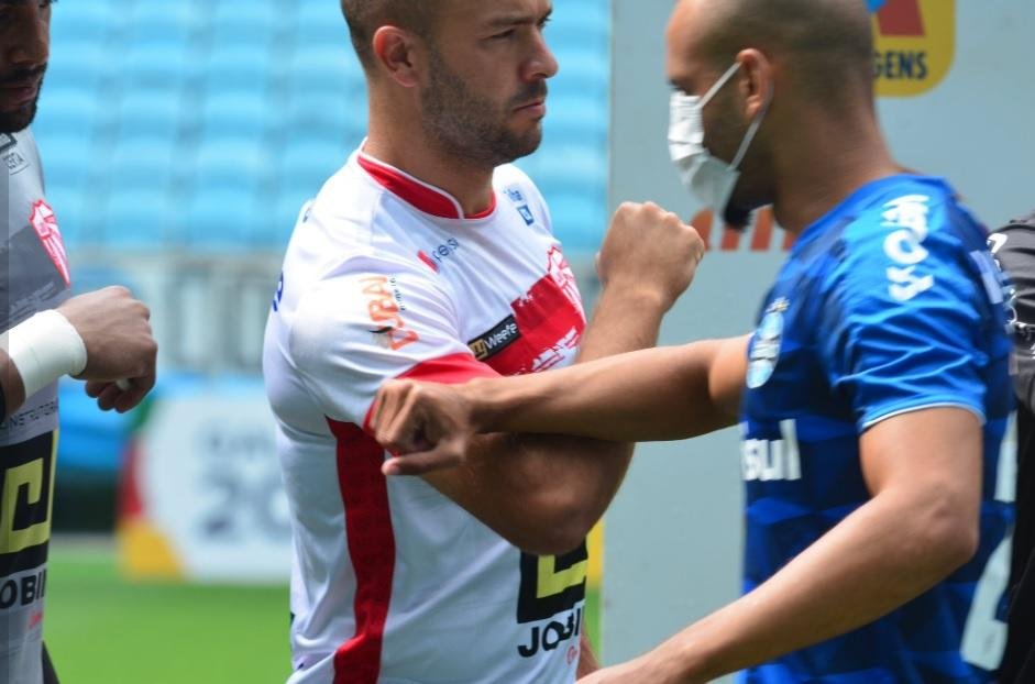 Jogadores gremistas com m&aacute;scaras e o cumprimento usando apenas o antebra&ccedil;o