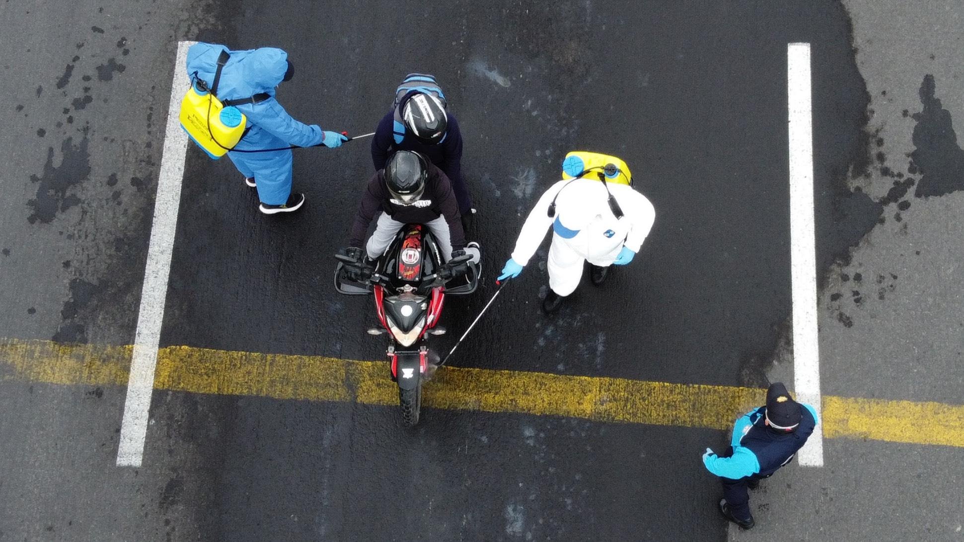 Agentes de sa&uacute;de desinfectam motocicleta no Equador