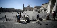 Os repórteres trabalham por uma barreira que fecha o acesso à Praça de São Pedro, no Vaticano