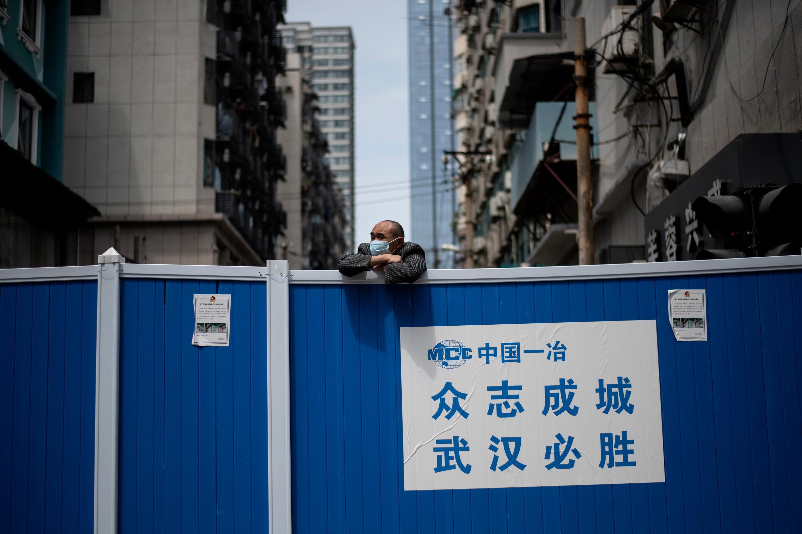 Um homem usando uma m&aacute;scara facial olha para uma barricada constru&iacute;da para manter as pessoas fora de um complexo residencial em Wuhan, na prov&iacute;ncia de Hubei, na China, em 14 de abril de 2020.