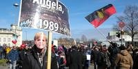 Manifestante levanta placa com mensagem contra Angela Merkel