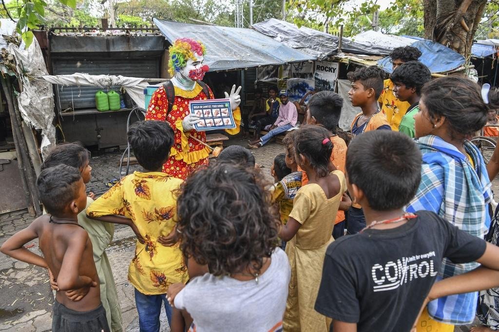 Ashok Kurmi, vestido de palha&ccedil;o, interage com as crian&ccedil;as enquanto as ensina a seguir os protocolos de seguran&ccedil;a contra o coronav&iacute;rus