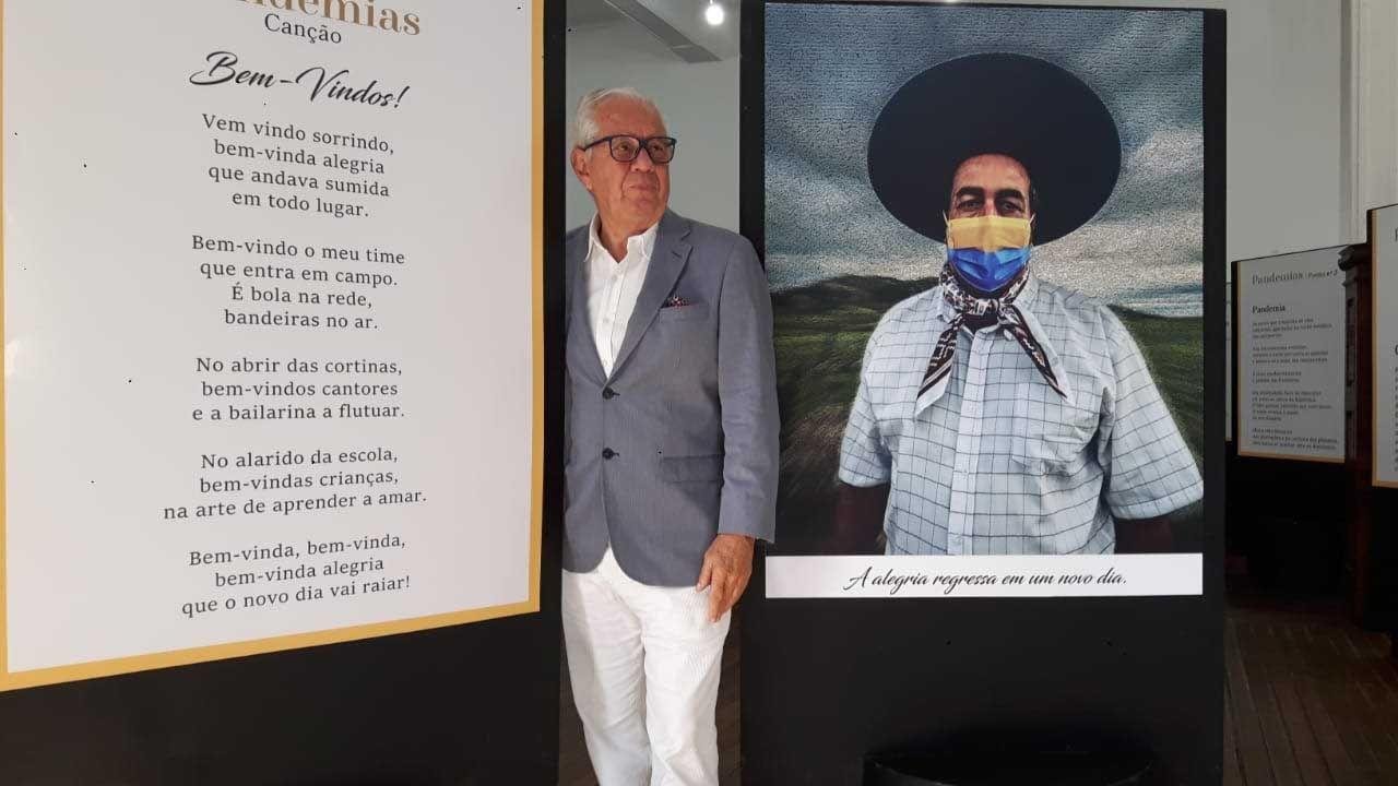 Poeta Luiz Coronel junto a banners de poema e de foto na mostra &lsquo;Pandemias&rsquo;