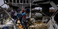 Ucranianos atravessam uma ponte destruída enquanto fogem da cidade de Irpin, a noroeste de Kiev