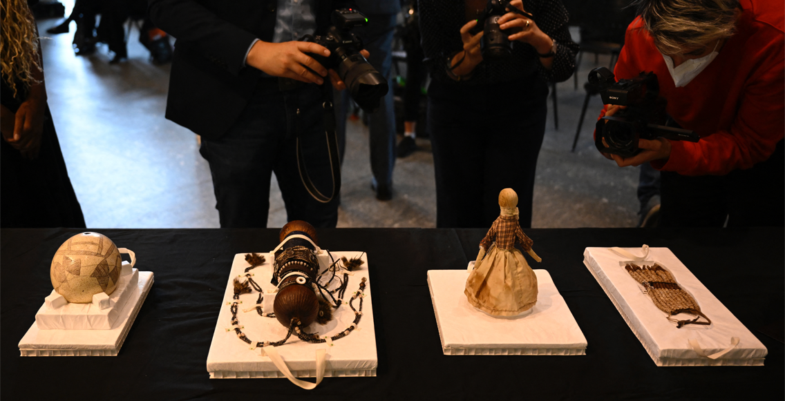 Entre os objetos est&atilde;o um vaso decorado com tr&ecirc;s cabe&ccedil;as, uma boneca em trajes tradicionais, v&aacute;rios acess&oacute;rios de cabelo e lan&ccedil;as