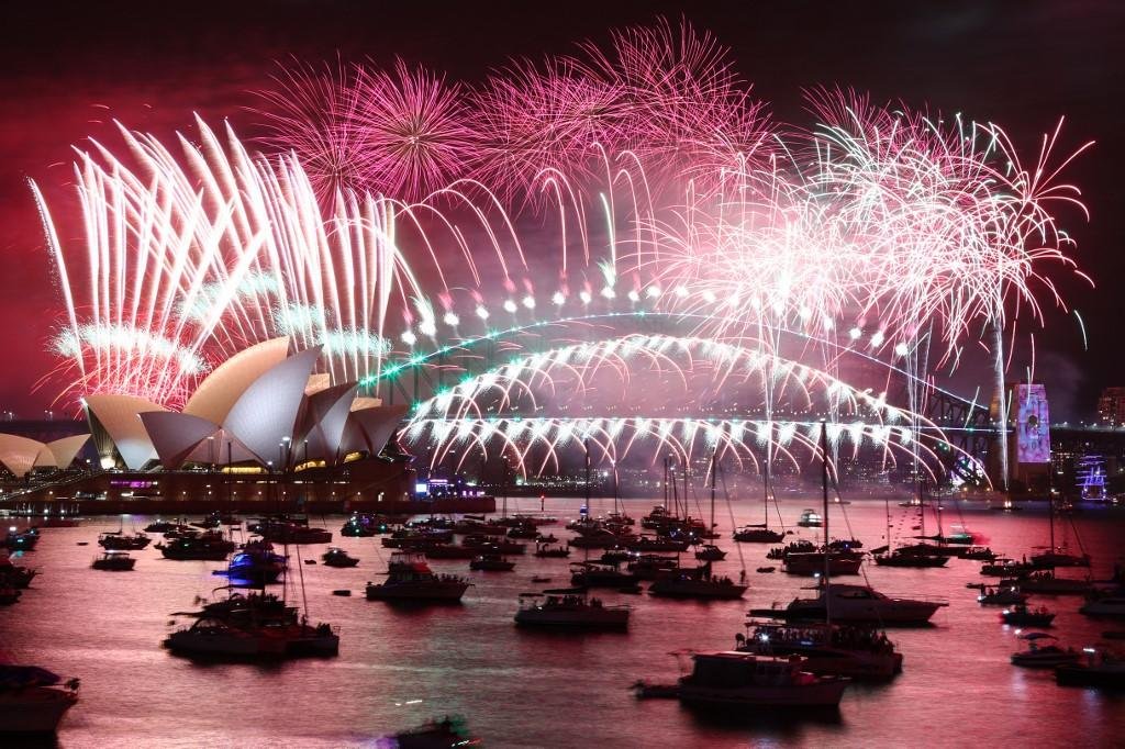 Ocupantes dos barcos e navios, na Ba&iacute;a de Sydney, acompanham de perto a queima de fogos