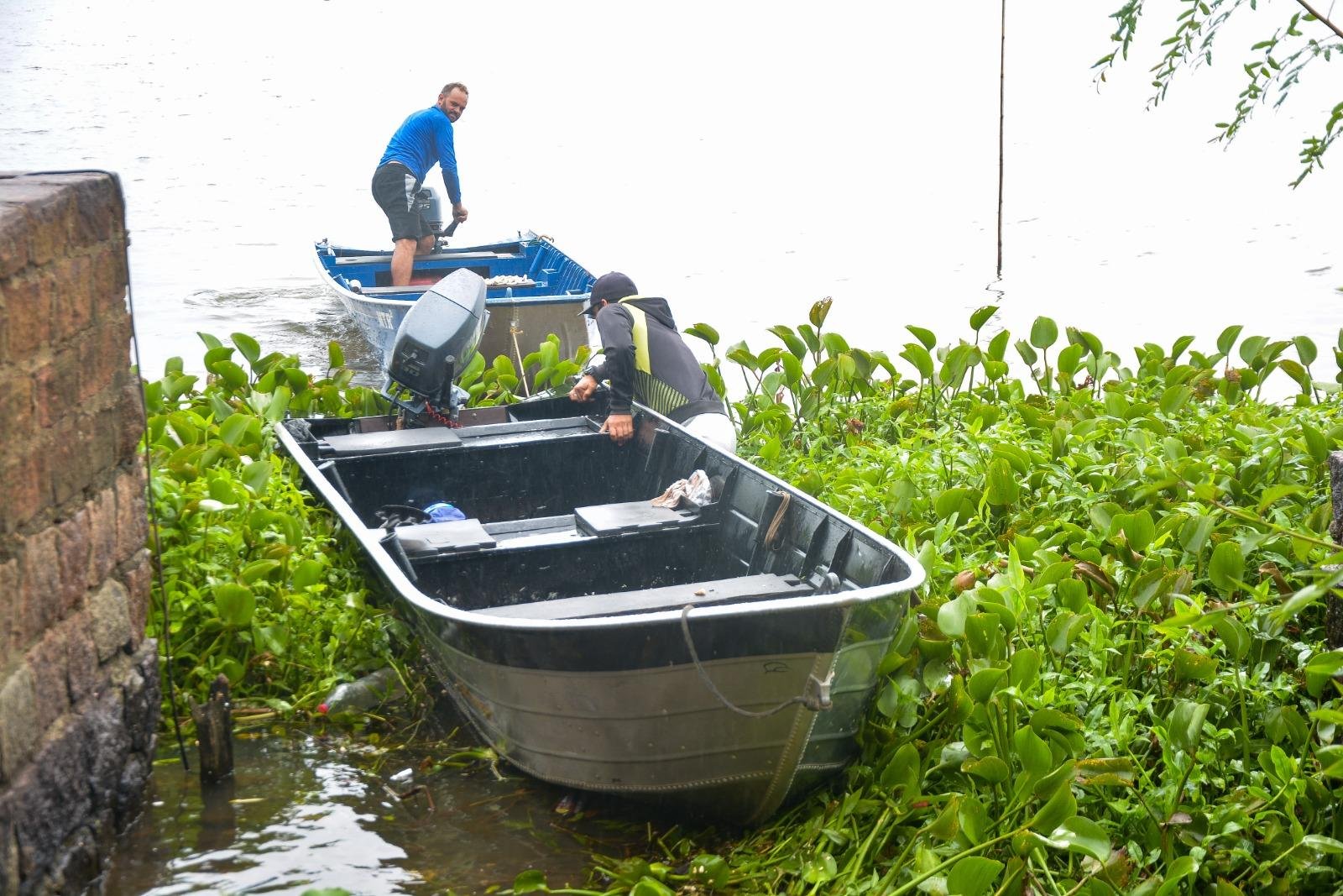 Marcelo e Alexandre tiveram dificuldades para retirar barcos com o ac&uacute;mulo de plantas ontem
